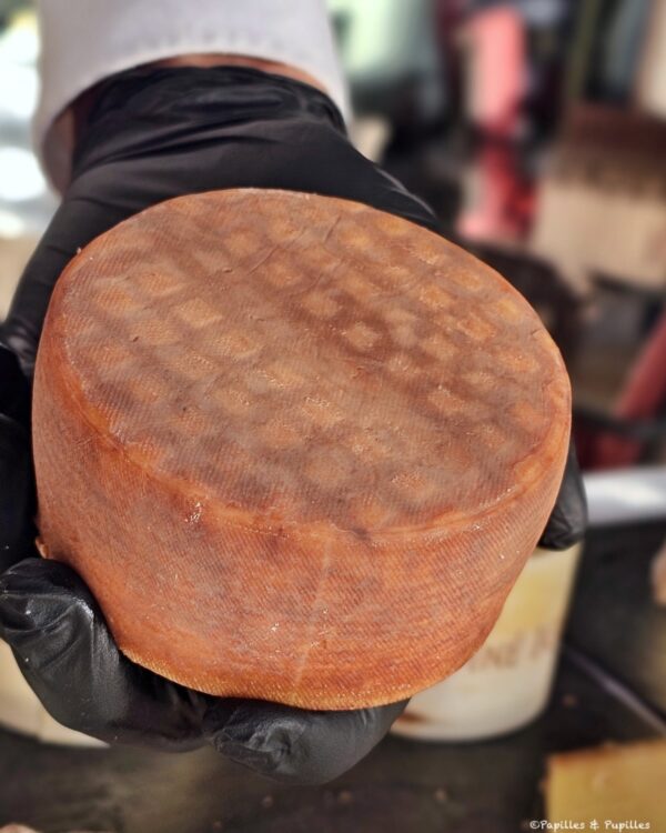 Fromage Trappe Échourgnac présenté entier par une main gantée noire